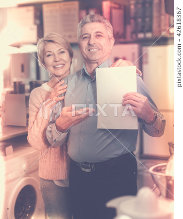 Charming mature couple buying on credit agreement for home appliances 42618367