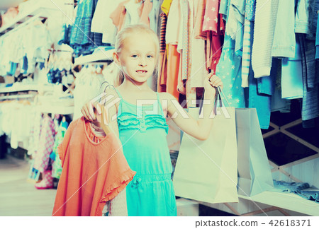 portrait of girl standing in kids clothes store with shopping bags 42618371