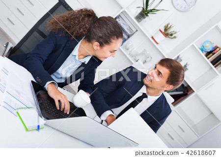 Two business male and female assistants wearing formalwear having work conversation Two business male and female assistants wearing formalwear having work conversation 42618607