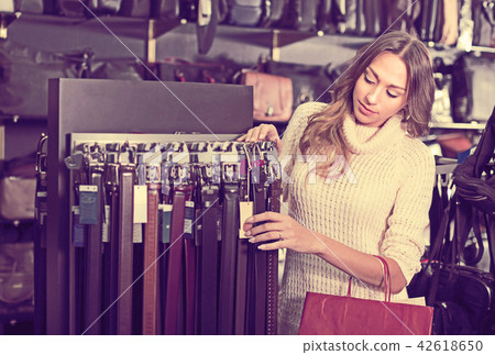 Smiling woman choosing fashion belts Smiling woman choosing fashion belts 42618650