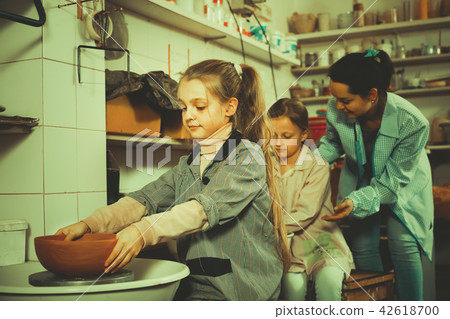 teacher helping girls to work on the potter's wheel teacher helping girls to work on the potter's wheel 42618700