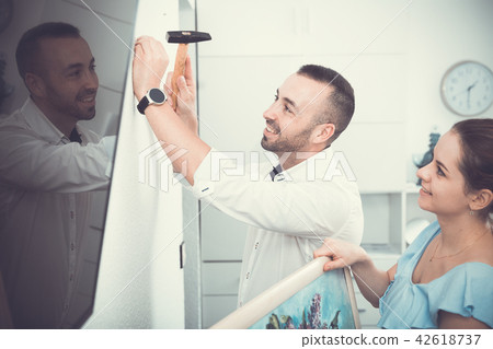 Female and her husband are hanging picture together 42618737