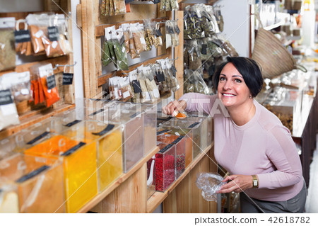 Mature woman standing next to containers with spices 42618782