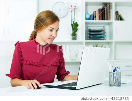 Woman sitting at office and working with laptop Woman sitting at office and working with laptop 42618785