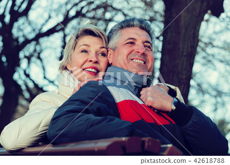 Smiling mature couple relaxing in park Smiling mature couple relaxing in park 42618788