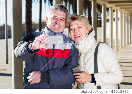 mature husband and wife make selfie on cell phones for walk mature husband and wife make selfie on cell phones for walk 42618882