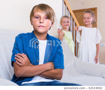 Two girls talking and sulky boy sitting separately at home Two girls talking and sulky boy sitting separately at home 42619082