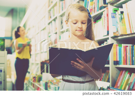 Girl reading textbook in bookstore Girl reading textbook in bookstore 42619083