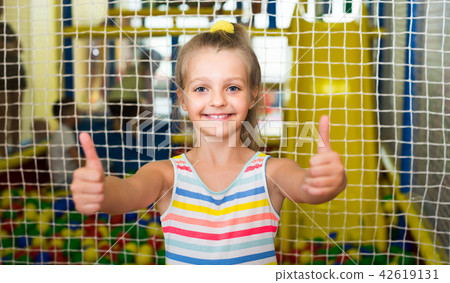 girl in bright dress looking happy and standing on indoor playground girl in bright dress looking happy and standing on indoor playground 42619131