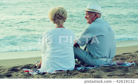 female and male in hat sitting on the beach female and male in hat sitting on the beach 42619132
