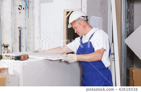 Contractor installing drywall construction Contractor installing drywall construction 42619338