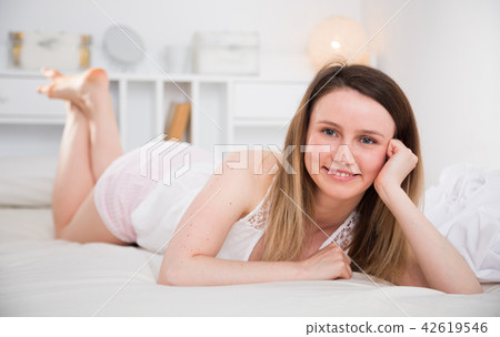 Cute girl in sleepwear lounging in bed in home interior Cute girl in sleepwear lounging in bed in home interior 42619546
