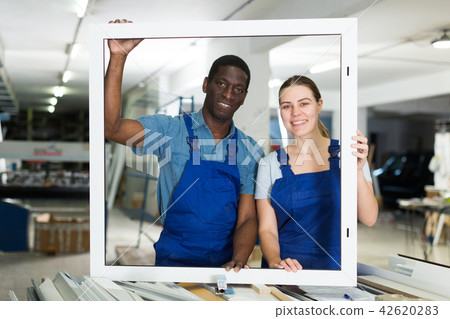 Two masters are working with window frame 42620283