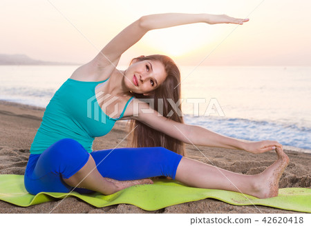 Smiling young woman in blue T-shirt is practicing stretching 42620418