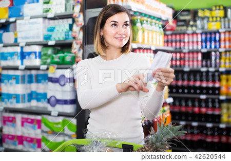 woman consulting shopping list in supermarket 42620544