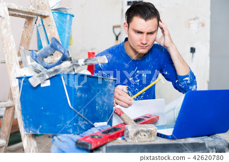 Male contractor working with papers and laptop Male contractor working with papers and laptop 42620780
