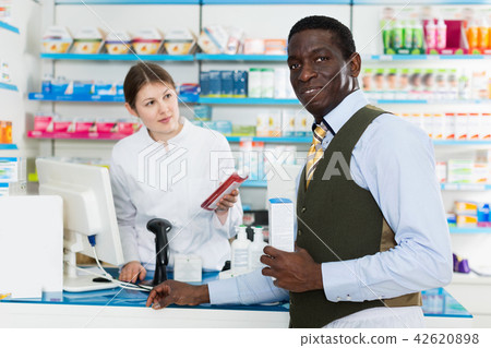 Portrait of smiling African American male customer buying medications in modern pharmacy Portrait of smiling African American male customer buying medications in modern pharmacy 42620898