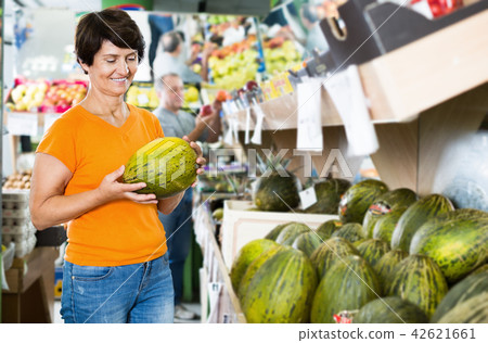 Smiling mature woman is choosing green melon 42621661