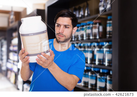 Serious attractive sport man looking different sport nutrition 42621673