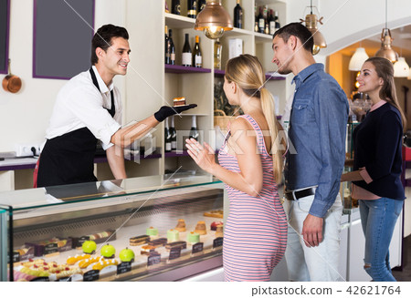 Man seller serving visitors in cozy pastry store Man seller serving visitors in cozy pastry store 42621764