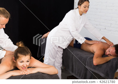 females masseurs doing massage at back young married couple, who lying on a massage table in a beauty salonfemales masseurs doing massage at back young married couple, who lying on a massage table in a beauty salon 42621780