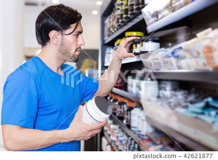 Serious muscular guy choosing sport dietary supplements 42621877