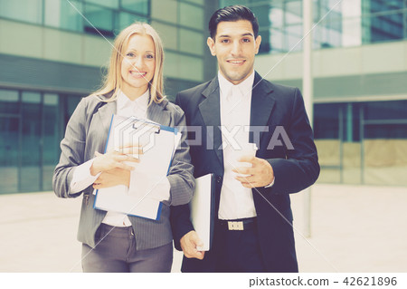 Businesswoman and her partner are standing with folder and coffee Businesswoman and her partner are standing with folder and coffee 42621896