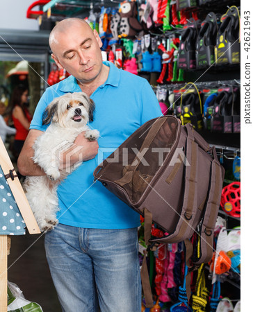 Portrait of young man with small dog standing in pet store 42621943