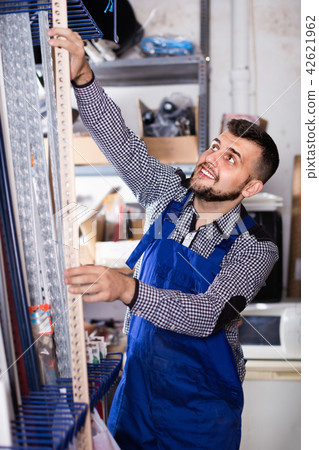 Young man worker examining plastic corners for tiles and floors 42621962