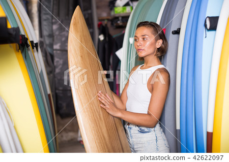 cheerful woman choosing colorful surfboard in the modern shop 42622097