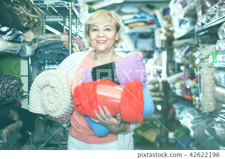 Adult female buyer choosing colour plaids in the textile store 42622196