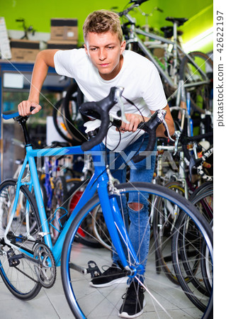 Male standing near the cycle in the shop 42622197