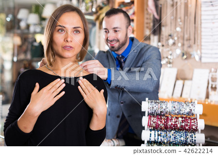 male worker helps to trying chainlet with pendants 42622214