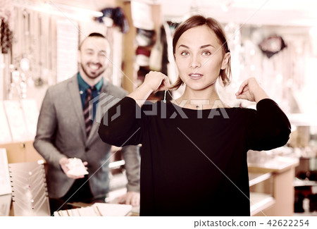 Female consumer trying chainlet with pendants 42622254