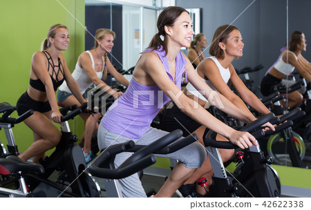 women on cardio training on exercycles in health club women on cardio training on exercycles in health club 42622338