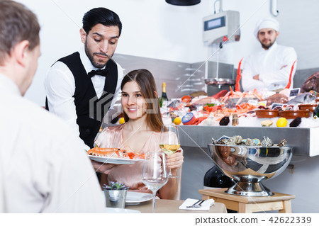 Young woman nicely spending time with male in fish restaurant Young woman nicely spending time with male in fish restaurant 42622339