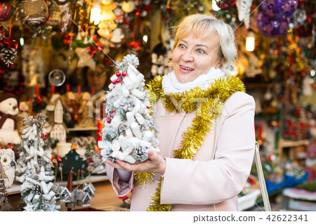 Female choosing decorative fir-tree Female choosing decorative fir-tree 42622341