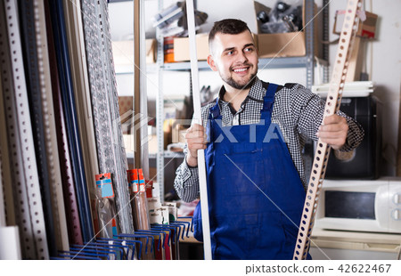 worker choosing plastic edging for tiles and flooring in workshop 42622467