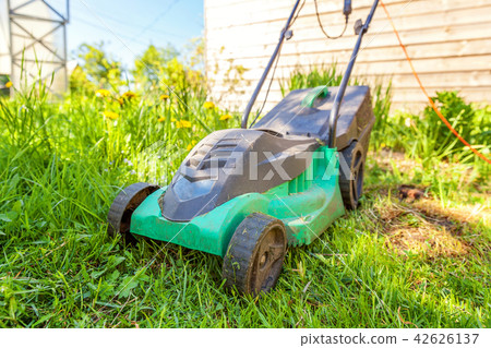 Lawn mower cutting green grass in backyard 42626137