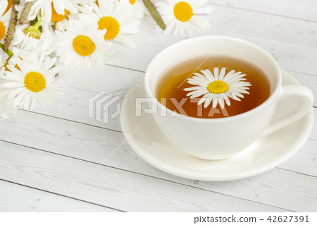 Cup of chamomile tea on a white wooden table. Cup of chamomile tea on a white wooden table. 42627391