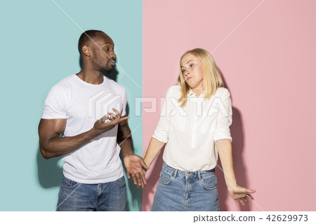 Beautiful female and male portrait on pink and blue studio backgroud. The young emotional couple 42629973