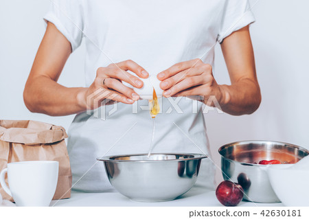 Woman wearing white t-shirt breaking egg  42630181