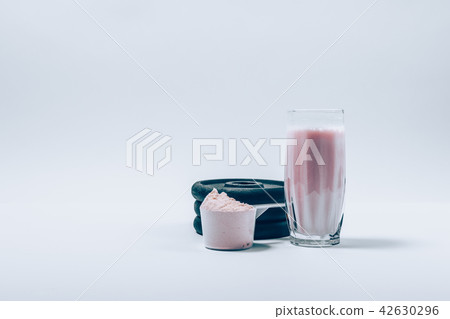 Whey protein shake in glass next to scoop  42630296