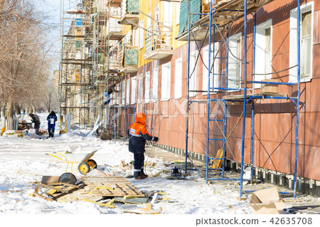 Workers warm and repair the facade of building. 42635708