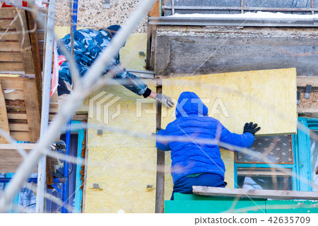 Workers warm and repair the facade of building. 42635709