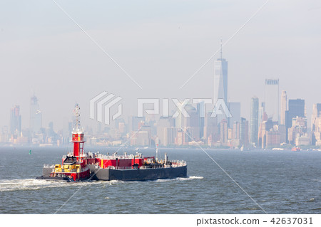 Freight tug pushing cargo ship to the port in New York City and Lower Manhattan skyscarpers skyline Freight tug pushing cargo ship to the port in New York City and Lower Manhattan skyscarpers skyline 42637031