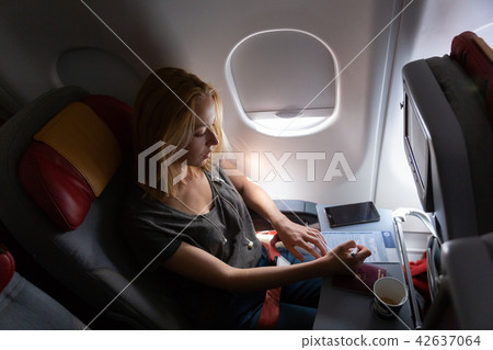 Casual woman flying on commercial passengers airplane, filling in immigration form. Casual woman flying on commercial passengers airplane, filling in immigration form. 42637064