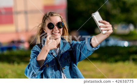 A teenage girl. Summer in nature. In his hands holds a smartphone. Take pictures of yourself on 42638775