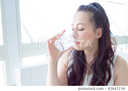 A woman drinking water with a cup 42641134