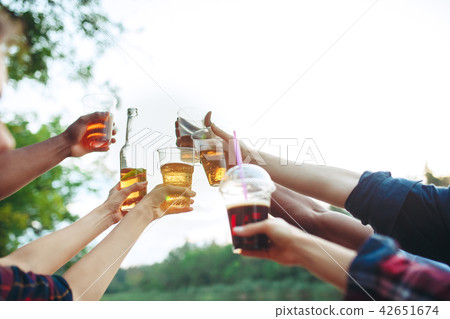 Bottles of beer in people's hands on blue sky background 42651674